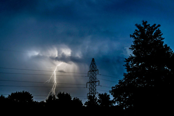 Photo of a thunderstorm showing lightning, clouds, power line and tower.